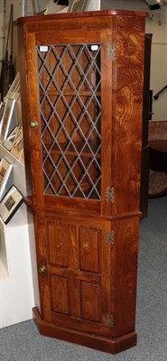 Lot 1276 - A modern oak standing corner cupboard with lead glazed upper section and panelled lower...