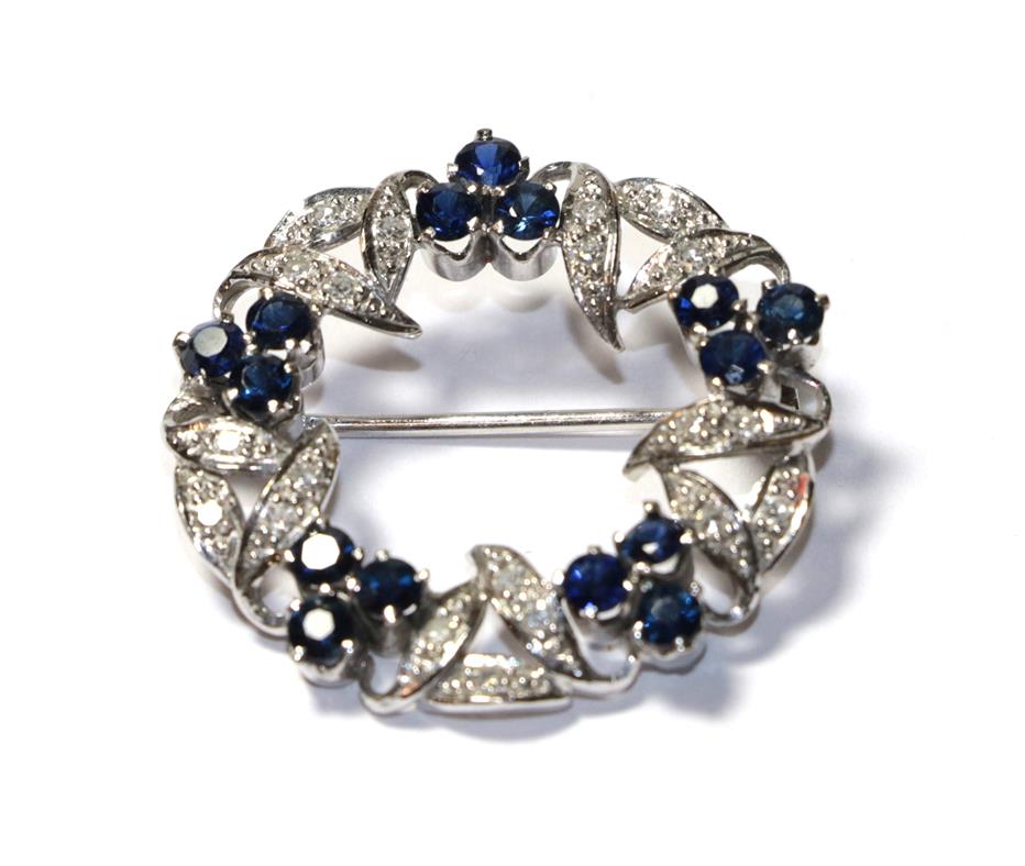 Lot 57 - A sapphire and diamond brooch, realistically modelled as a wreath, clusters of three round cut...
