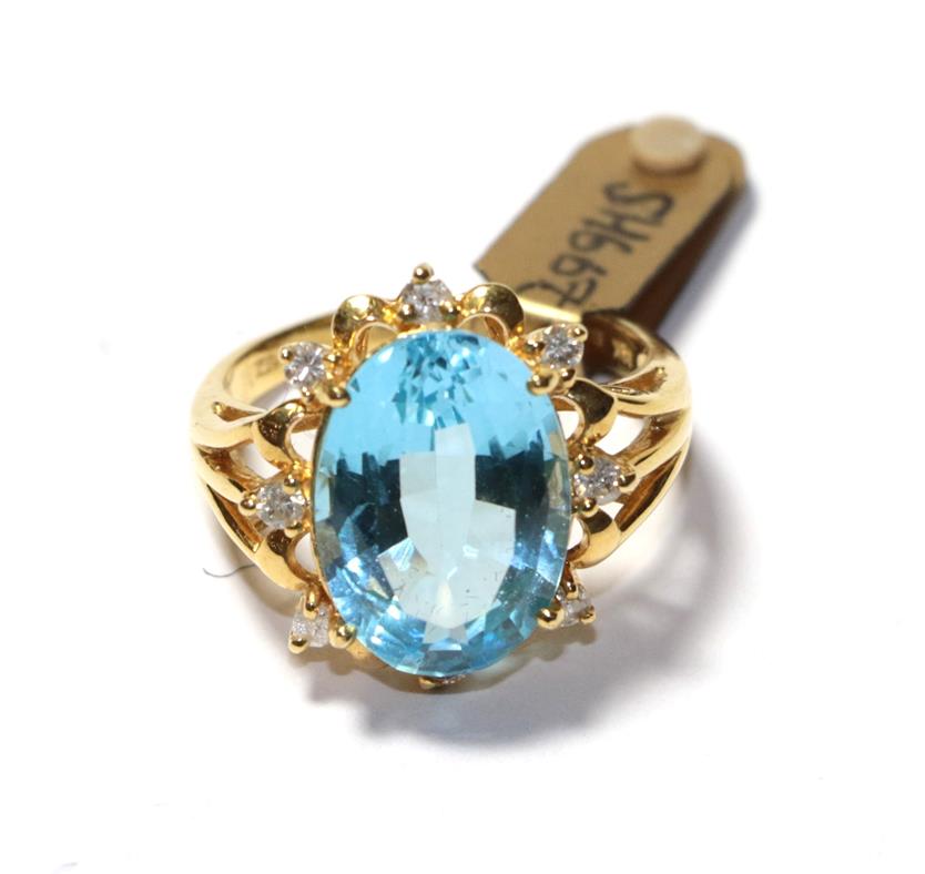 Lot 60 - An 18 carat gold blue topaz and diamond cluster ring, the oval cut blue topaz within a spaced...