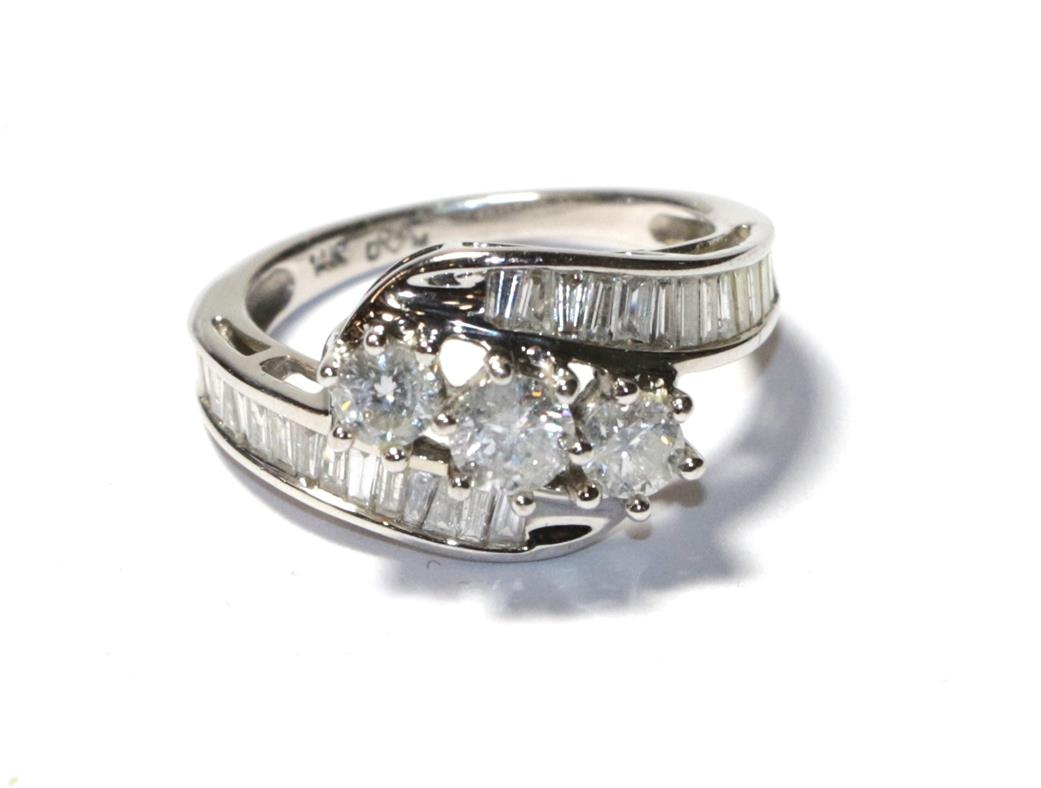 Lot 64 - A diamond three stone twist ring, the graduated round brilliant cut diamonds in white claw...