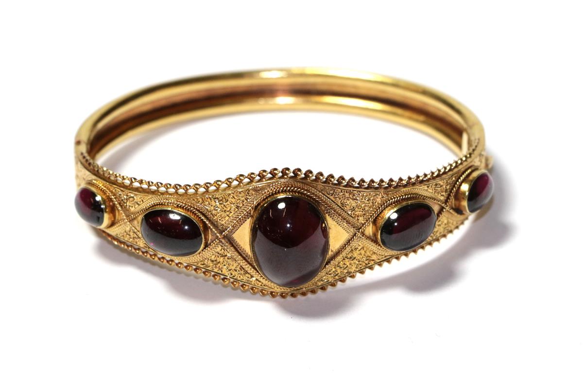 Lot 78 - A garnet hinged bangle, five graduated oval cabochon garnets in yellow rubbed over settings to...