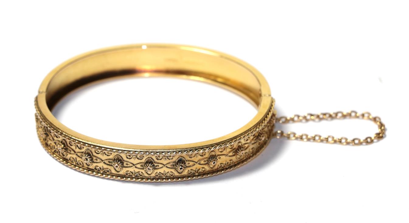 Lot 83 - A 15 carat gold hinged bangle with rope twist decoration, to a plain polished hinged back, measures