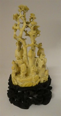 Lot 136 - A Japanese Meiji period carved ivory okimono on a hardwood stand, formed as a group of figures on a