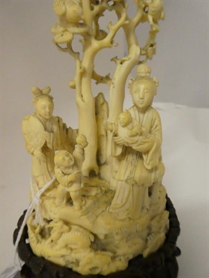 Lot 136 - A Japanese Meiji period carved ivory okimono on a hardwood stand, formed as a group of figures on a