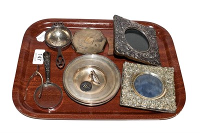 Lot 147 - A collection of silver items to include two repousse easel photograph frames, four pin dishes,...
