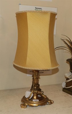 Lot 175 - A gilt bronze based table lamp, raised on a scalloped circular plinth over scroll supports