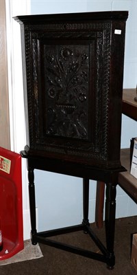 Lot 1286 - A Georgian carved oak corner cupboard on an associated later corner table, 75cm by 167cm