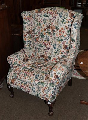 Lot 1296 - A Georgian style upholstered wing back armchair on ball and claw supports