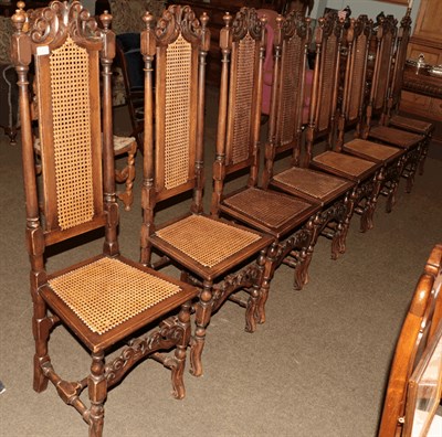 Lot 1305 - A set of ten carved walnut dining chairs in the Baronial style with cane work seats and back...