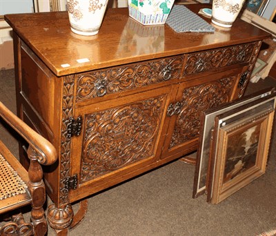 Lot 1311 - An oak side cabinet with armorial carved panels on bulbous supports with cross stretcher (en...