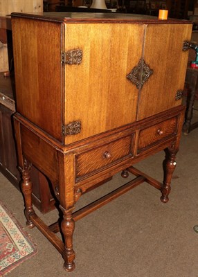 Lot 1324 - An oak cocktail cabinet raised on turned baluster supports with H-stretcher, 100cm by 52cm by...