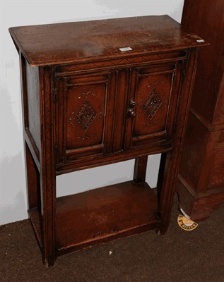 Lot 1344 - An oak side cupboard with carved panel doors, raised of carved square support with pot board,...