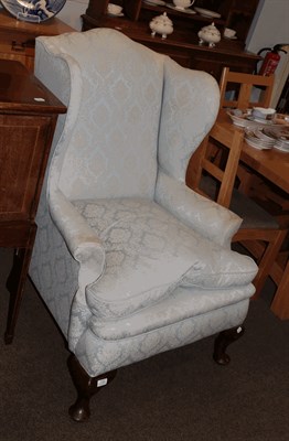 Lot 1352 - A Georgian style upholstered wingback armchair raised on cabriole legs