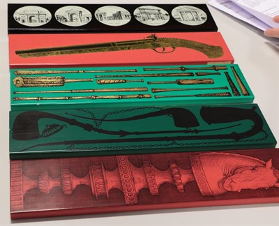 Lot 2081 - Five Fornasetti Lacquered Aluminium Boxes, with mouthpieces, pistol, Architectural doors/gates,...