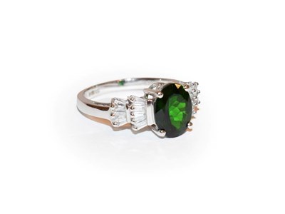 Lot 110 - A diopside and diamond ring, the oval cut diopside flanked by stepped tapered baguette cut...