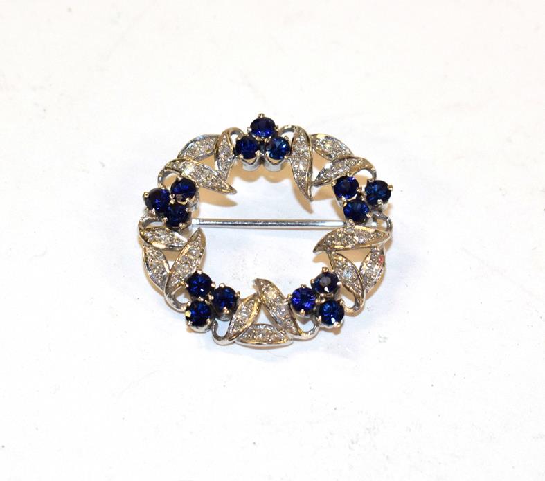 Lot 137 - A sapphire and diamond brooch, realistically modelled as a wreath, clusters of three round cut...