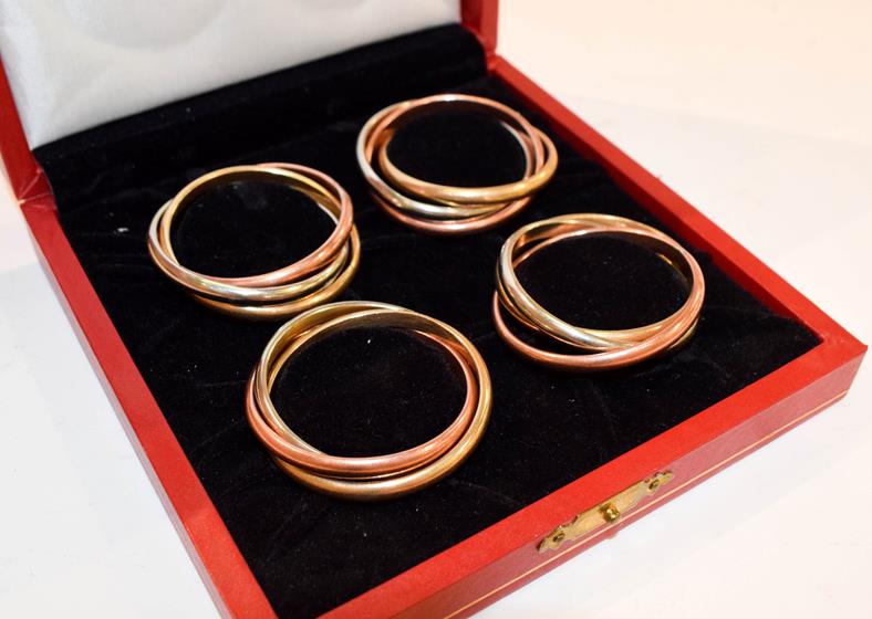 Lot 173 - A cased set of four silver plate and gilt plate napkin rings, retailed by Cartier, 20th...