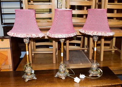 Lot 252 - A set of three modern metal effect table lamps, each 54cm high, with red stripe fabric shades (3)