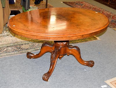 Lot 1062 - A Victorian figured walnut breakfast table with oval top, raised on four carved scrolling supports