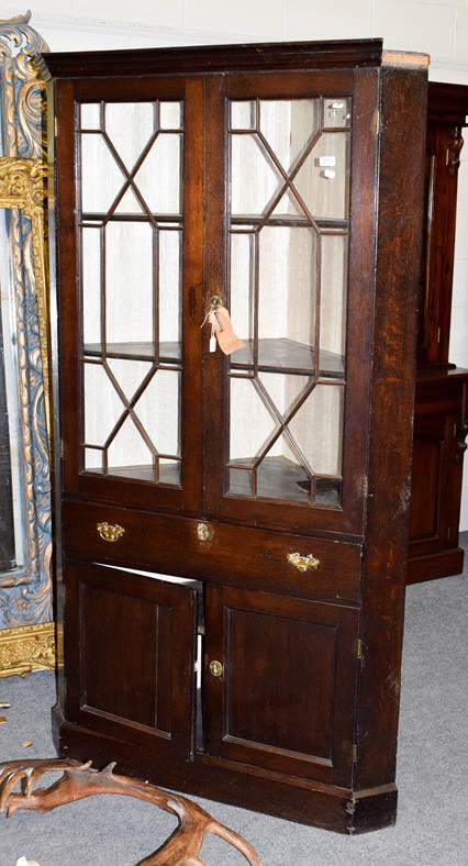 Lot 1091 - A mid 18th century oak free-standing corner cupboard, the moulded cornice above astragal glazed...