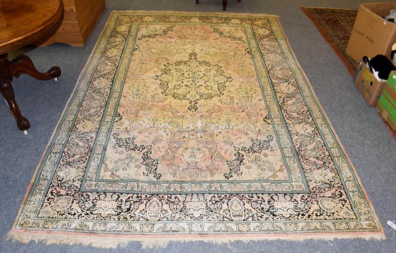 Lot 1100 - Kashmir silk piled carpet, the field with urns issuing flowers around a medallion framed by...