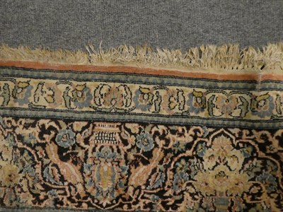 Lot 1100 - Kashmir silk piled carpet, the field with urns issuing flowers around a medallion framed by...