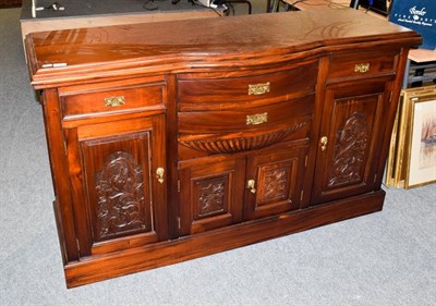 Lot 1104 - A reproduction bow fronted sideboard with stained finish and carved panels, 157cm by 54cm by 94cm