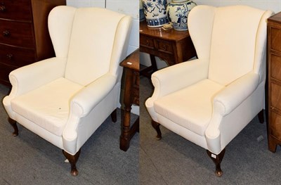 Lot 1117 - A pair of Georgian style wingback armchairs, raised on cabriole supports, upholstered white...