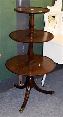 Lot 1122 - A George III mahogany three-tier dumb waiter on down swept legs terminating in brass caps and...