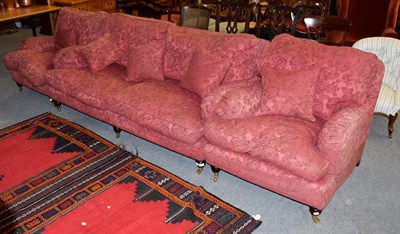 Lot 1192 - A 20th century upholstered three-piece suite, in the style of Howard & Sons, raised on turned...