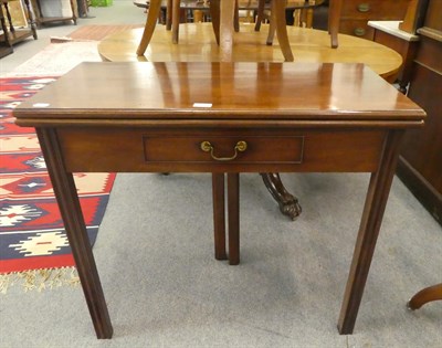 Lot 1204 - A George III mahogany fold-over tea-table, with single drawer and raised on reeded square supports
