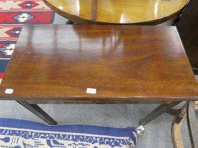Lot 1204 - A George III mahogany fold-over tea-table, with single drawer and raised on reeded square supports