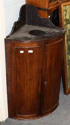 Lot 1218 - An oak bow-front hanging corner cupboard, 62cm by 110cm high