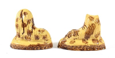 Lot 17 - A Pair of Buff Glazed Earthenware Figures of Lions, circa 1800, recumbent, on oval bases with...