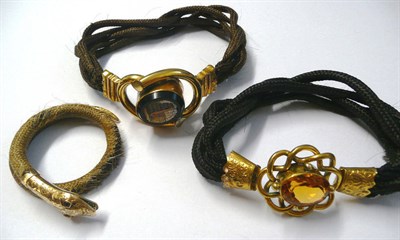 Lot 479 - Three Victorian Hair Bracelets, one of plaited fair hair, mounted with a snake's head and tail,...