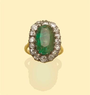 Lot 489 - An Emerald and Diamond Cluster Ring, an oval cut emerald within a border of old cut diamonds in...