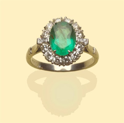 Lot 497 - An 18 Carat White Gold Emerald and Diamond Ring, an oval mixed cut emerald within a border of round