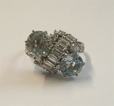 Lot 521 - An Aquamarine and Diamond Twist Ring, two round brilliant cut aquamarines spaced by a row of...