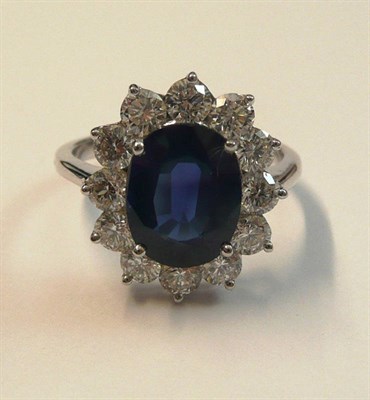 Lot 524 - A Sapphire and Diamond Cluster Ring, the oval mixed cut sapphire within a border of round brilliant