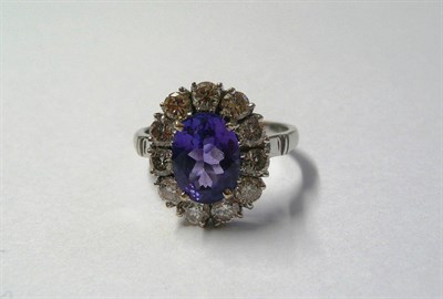 Lot 525 - An 18 Carat White Gold Tanzanite and Diamond Ring, the oval cut tanzanite within a border of...