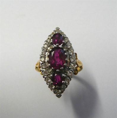 Lot 539 - A Ruby and Diamond Navette Ring, three graduated oval cut rubies within a border of round brilliant