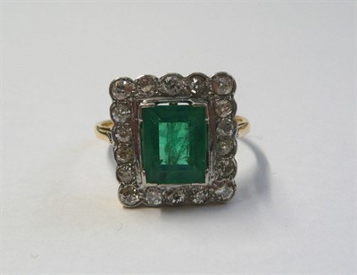 Lot 541 - An Emerald and Diamond Cluster Ring, the step cut emerald in a white claw setting, within a...