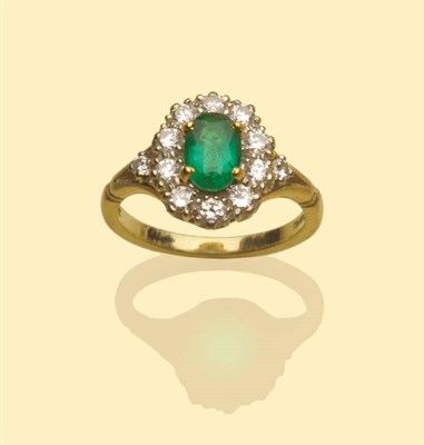 Lot 545 - An 18 Carat Gold Emerald and Diamond Cluster Ring, the oval cut emerald in a yellow four claw...