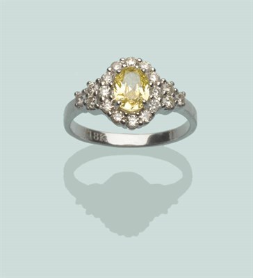 Lot 565 - A Diamond Cluster Ring, an oval cut yellow diamond within a border of white diamonds, with clusters