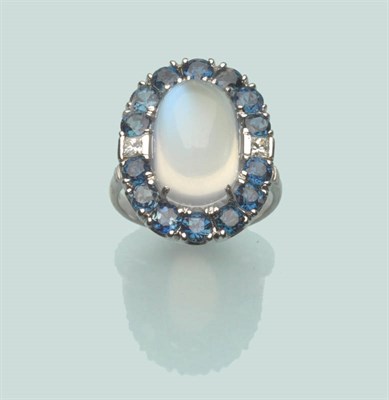 Lot 566 - An 18 Carat White Gold Moonstone, Sapphire and Diamond Cluster Ring, an oval cabochon moonstone...