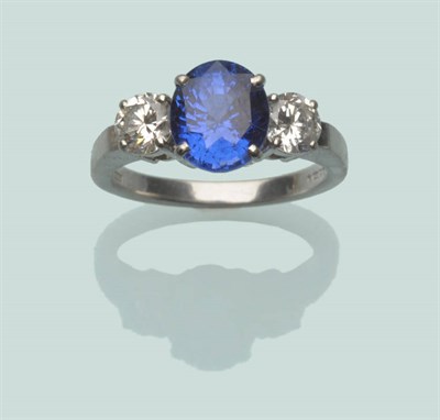 Lot 567 - A Platinum Sapphire and Diamond Three Stone Ring, the oval mixed cut sapphire flanked by a...