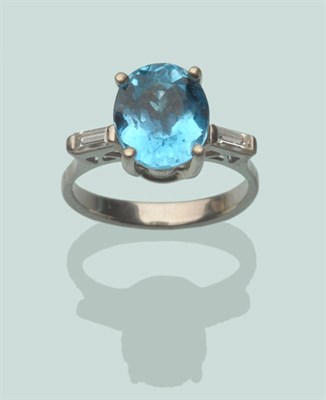 Lot 568 - A Blue Topaz and Diamond Ring, an oval blue topaz flanked by a baguette cut diamond to each...