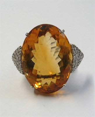 Lot 574 - An 18 Carat White Gold Citrine and Diamond Ring, the oval cut citrine flanked by a triangular...