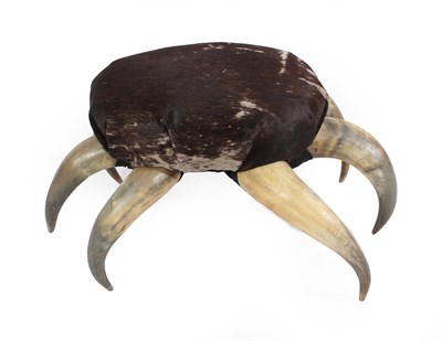 Lot 383 - A Cow Horn Footstool, the seat covered in cowhide, the six legs in the form of cow horns, 59cm...