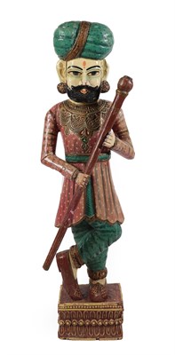 Lot 404 - A Painted Wood Figure of a Punjabi Attendant, standing cross-legged wearing a turban, holding a...